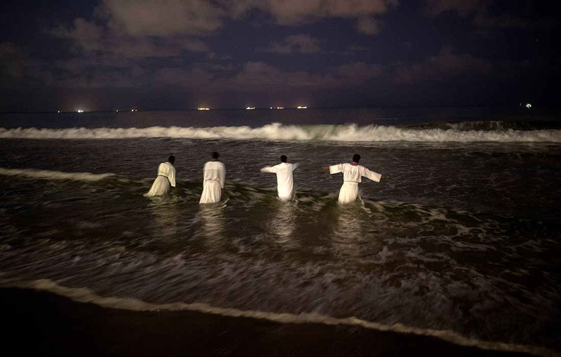 Священники заходят в море перед крещением верующих на пляже в Дурбане, Южная Африка