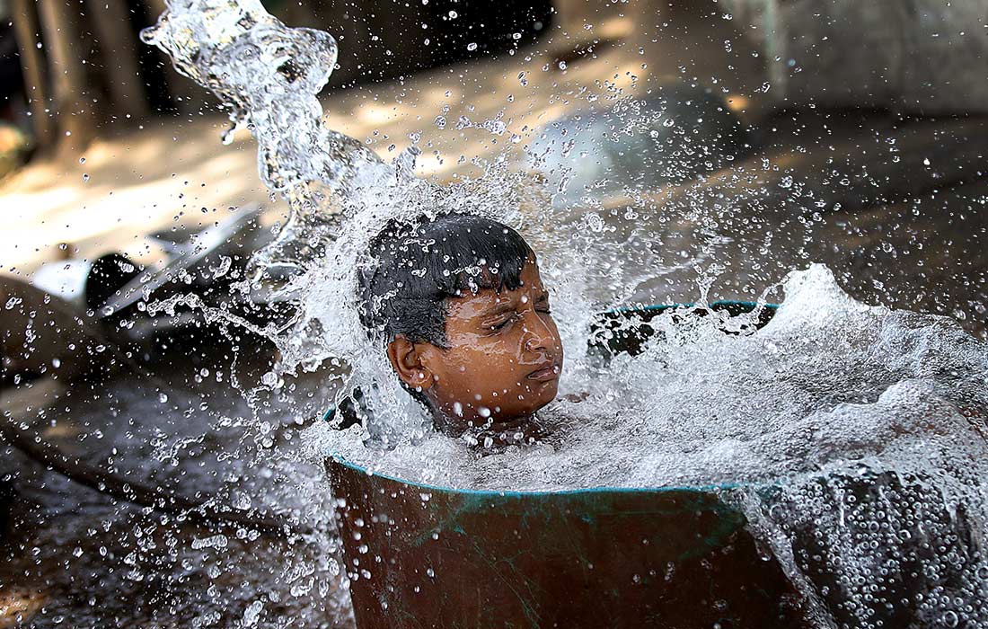 Мальчик купается в трубчатом колодце в жаркий день в Нью-Дели